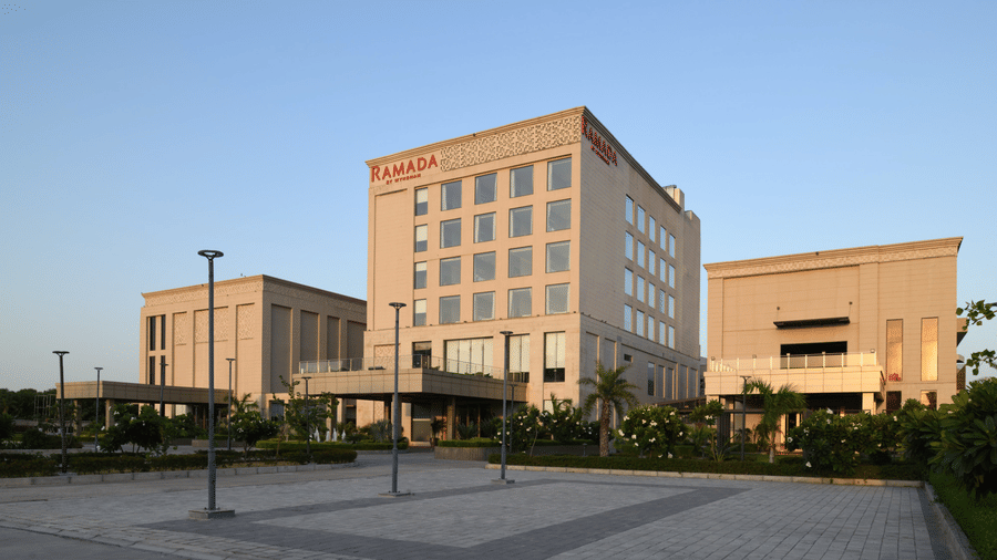 Daytime exterior view of Ramada by Wyndham Sonipat Murthal showcasing its contemporary architecture and expansive entrance area.