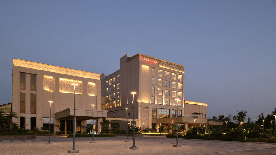 Illuminated evening façade of Ramada by Wyndham Sonipat Murthal with modern design and grand entrance area.
