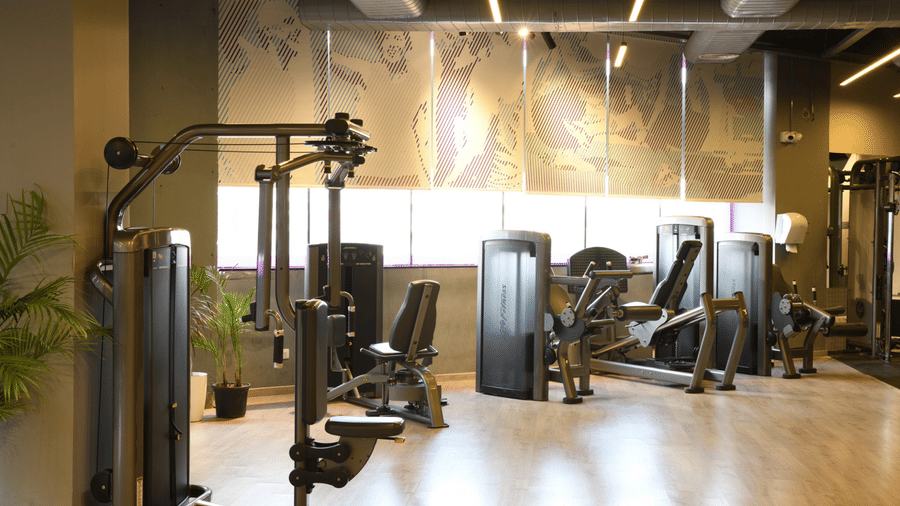 Indoor fitness centre with strength training equipment and open workout space | Ramada Encore by Wyndham Gurugram Dwarka Expressway