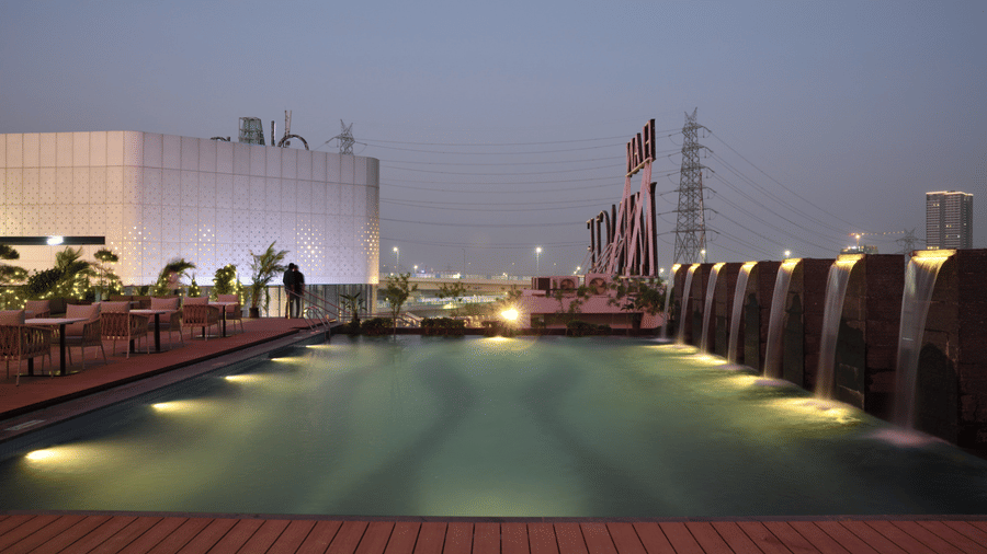 Rooftop swimming pool with ambient lighting and open skyline backdrop | Ramada Encore by Wyndham Gurugram Dwarka Expressway