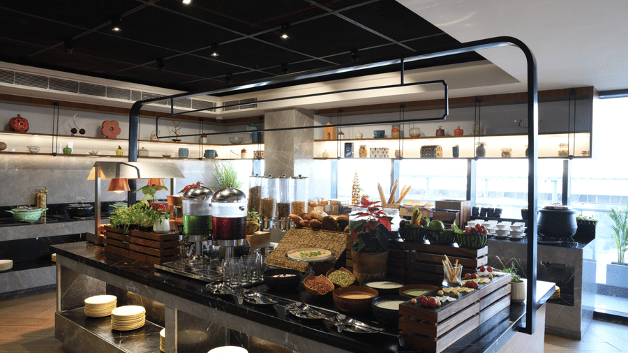 Elegant buffet setup with breads, cereals, fresh produce, beverages, and live dining stations | Ramada Encore by Wyndham Gurugram Dwarka Expressway