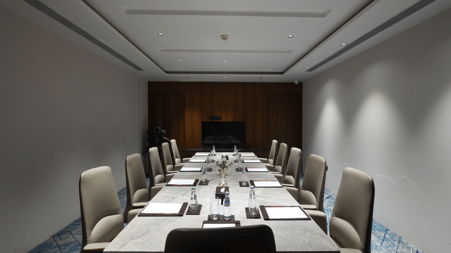 Tulip hall featuring a long conference table, executive chairs, and a presentation-ready layout | Ramada Encore by Wyndham Gurugram Dwarka Expressway