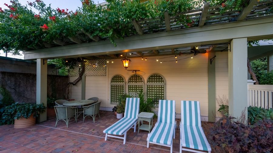 A well-lit outdoor lounge area of Tallman Hotel with sun beds and potted plants.