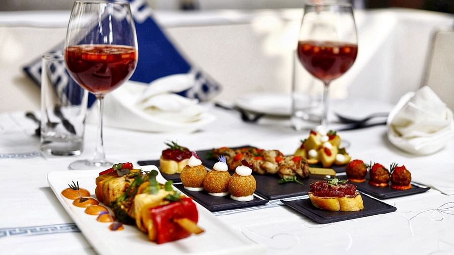 image of a platter of indian starters served with two glasses of wine on a table - The Claridges New Delhi