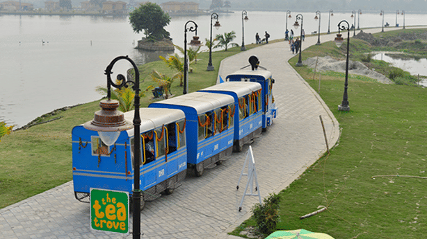 Toy train travelling along a landscaped pathway beside the waterfront at Eco Park, Kolkata.