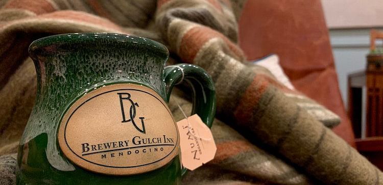 A mug with a logo rests on a patterned fabric.