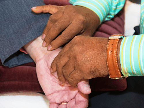 A person taking the pulse of another person by holding their wrist