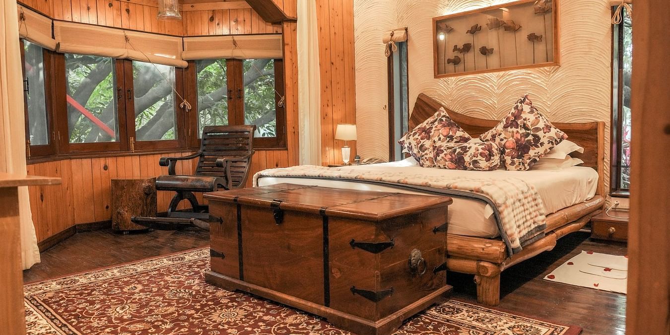 A bedroom with a patterned rug, a bed, and warm lighting, wooden interior - The Den Corbett Resort & Spa, Kumeria.