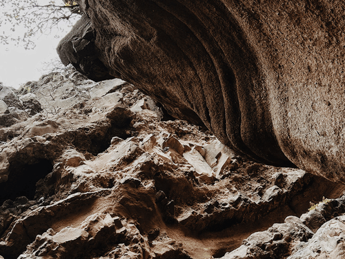 A naturally formed rock cave featuring rugged stone textures, unique formations, and an adventurous atmosphere.