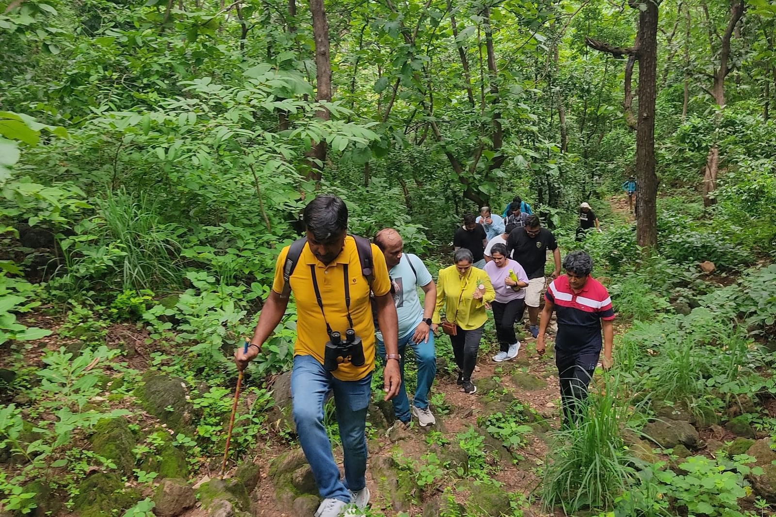 A group of people trekking around the forest area on a narrow rugged path at Daksh Resort and Amusement Park.