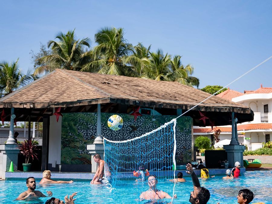 Guests playing water volleyball in the swimming pool at Heritage Village Resorts & Spa, Goa.