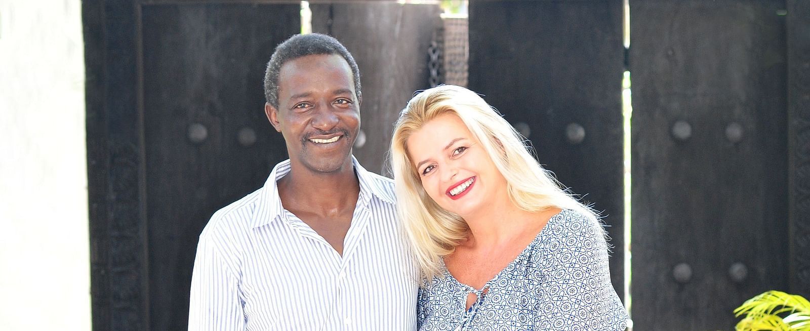 View of the owner Elly and his wife Christine standing infront of a gate at shooting star Boutique Hotel