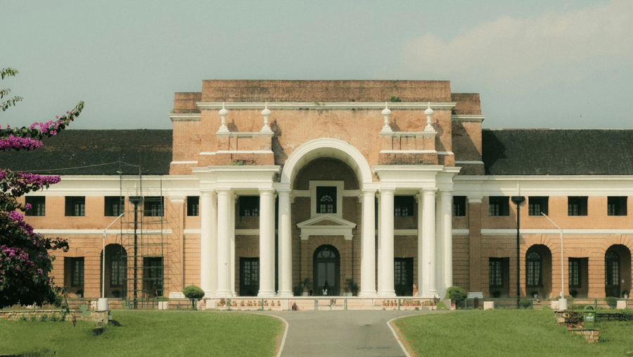 Facade of the Forest Research Institute, one of the top tourist places in Dehradun, Uttarakhand, with manicured lawns in between a pathway leading to the entrance.