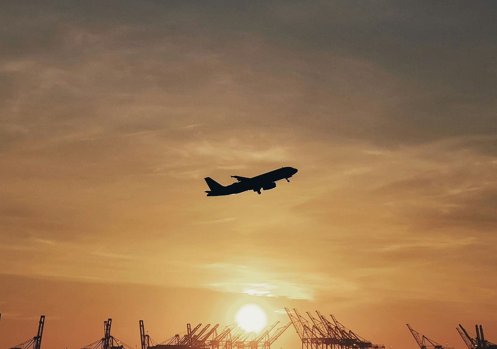 An image sunset with a plane flying.