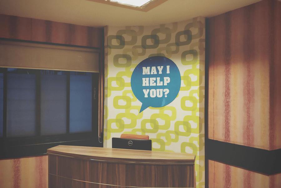 Reception desk with a May I Help You sign in the lobby of Lime Tree Luxury Studio, Gurgaon