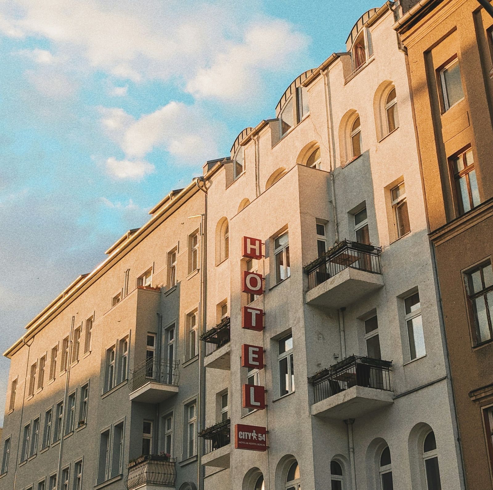  A low-angle view of a row of European-style buildings with balconies under a blue sky
