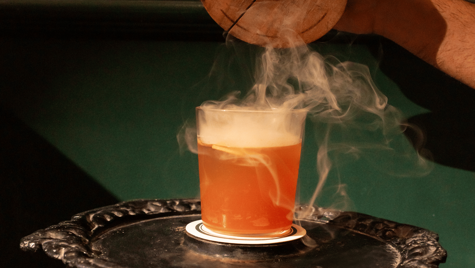 A dramatic smoked cocktail experience at Panna Villas Palace, with aromatic smoke pouring from a wooden lid into a citrus-infused drink on a vintage black tray.