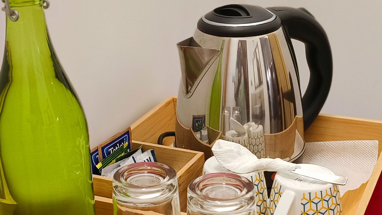 A tea and a coffee maker kept in a tray with cups and a green water bottle in 103 room at Ananda Holiday Home, Wayanad 1