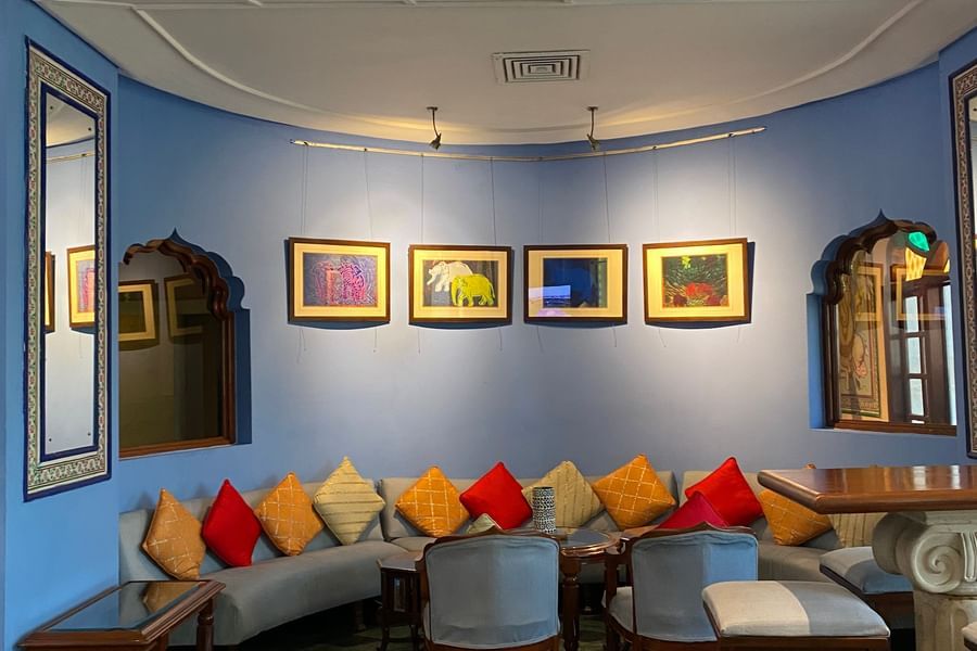 A calming blue wall with four framed paintings with seating for the guests at ta BLU Rooftop Bar at Clarks Amer, Jaipur