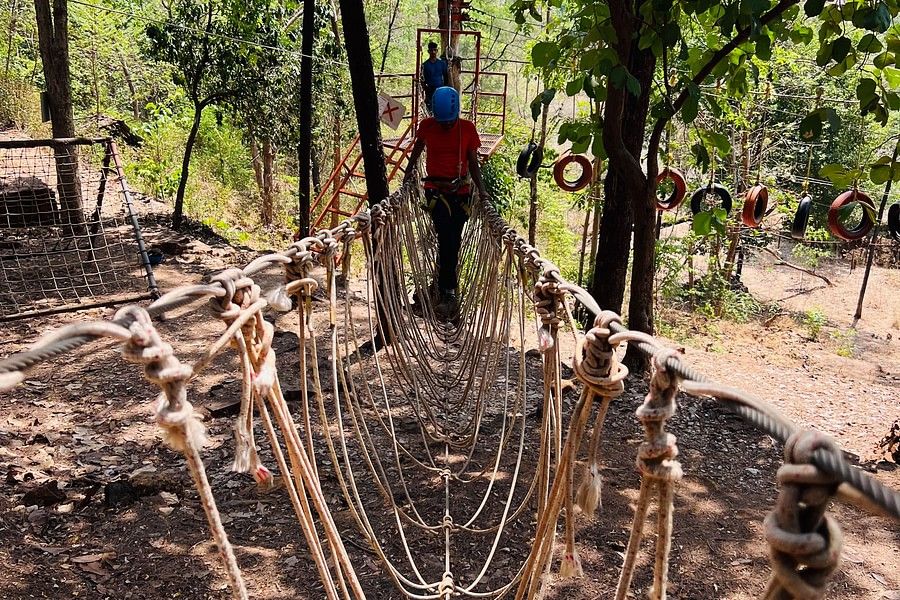 alt-text An image showing a girl standing at the other side of the burma bridge facing the camera while looking down