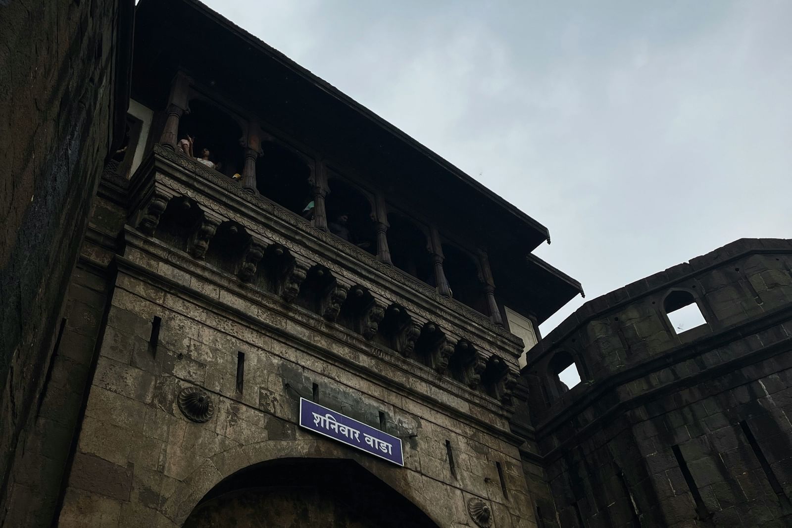 Historic stone gateway with intricate arches against cloudy sky.