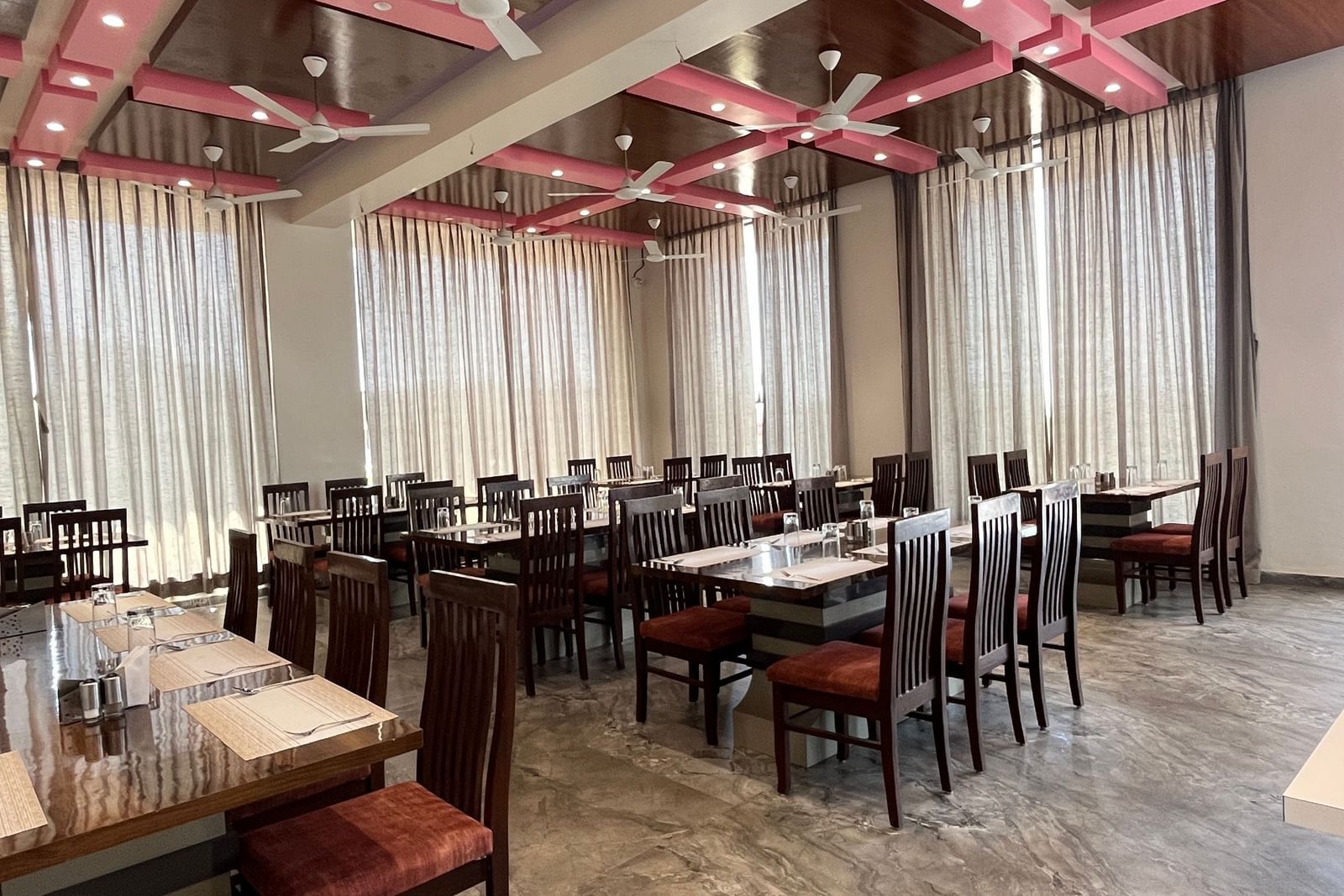 Extended view of the spacious and neatly arranged tables in the fine-dining restaurant at Daksh The Valley Resort, Saputara.