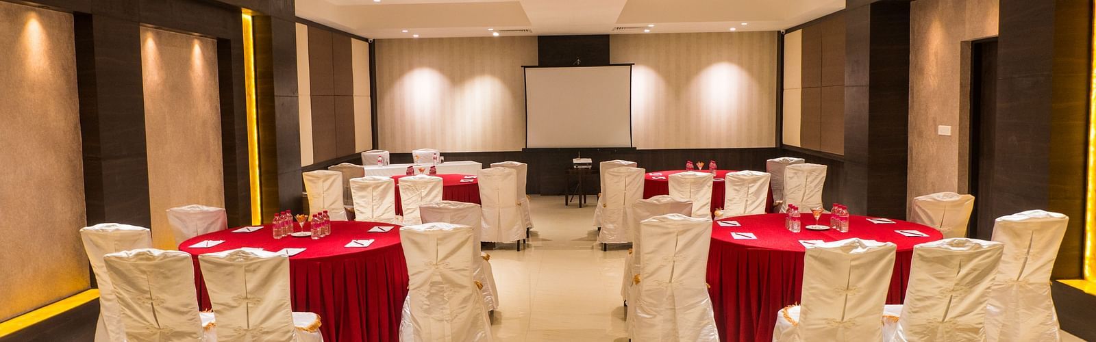 event hall with red tables and white satin chairs of ASR Parklane, Hosur