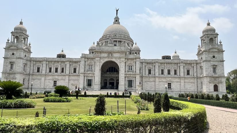 A grand historical monument with domes and towers, surrounded by a well-maintained garden and pathway.