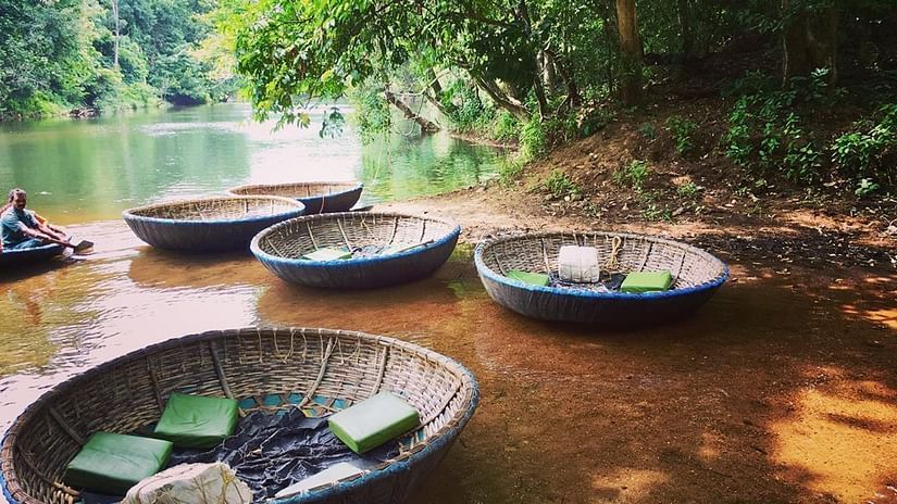 Circular coracle boats floating by the riverbank, ready for a traditional riverboat ride in a forested area - Black Thunder, Coimbatore