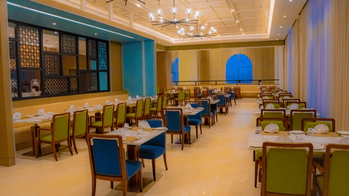 A bright dining hall featuring long rows of tables and chandeliers - Serene Sarovar Premiere Hargeisa