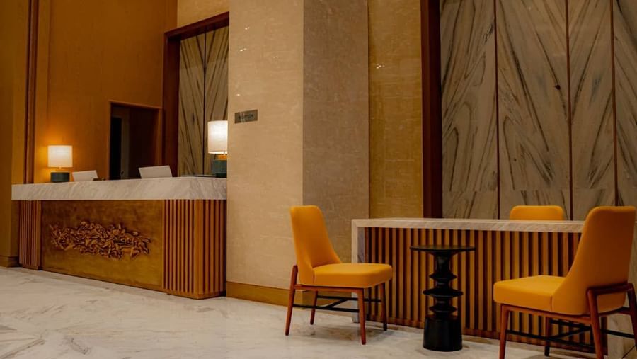 Frontal shot of a reception desk featuring golden floral design inside our hotel, with a waiting area beside it - Serene Sarovar Premiere Hargeisa