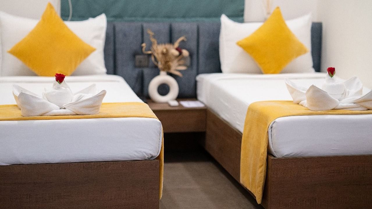 A twin room with two neatly made beds, accented with pillows and a decorative centrepiece on the bedside table at Hotel Kyzen Smartstays – Smart, Reliable, Kyzen