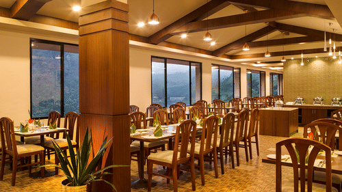 Restaurant interior highlighting the wooden pillars, exposed beams, and pendant lighting - Abad Copper Castle, Munnar