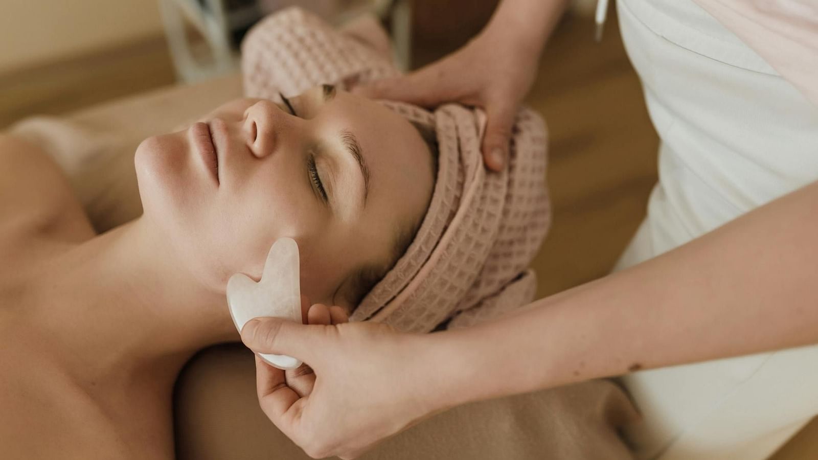 A woman receiving a facial massage with a gua sha tool