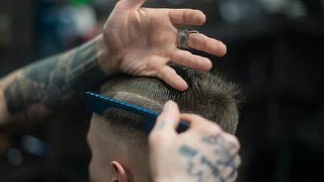 A person sitting while another person combs their hair during a haircut