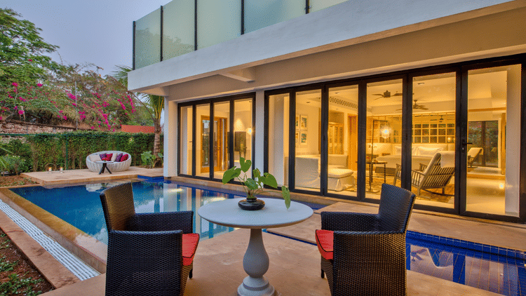 A view of the sit out area near the private pool of an Azaya XL Pool Suite with ceiling to floor windows on the building next to the pool at Azaya Beach Resort, Goa, A South Goa stay near the beach.