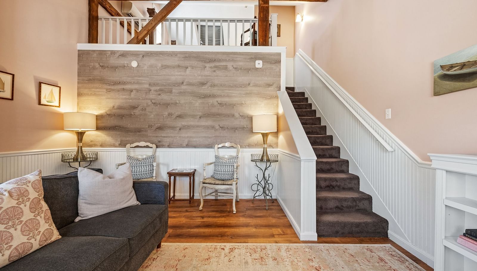A room with sofa, wood accent wall, and stairway leading to loft at Hartstone Inn