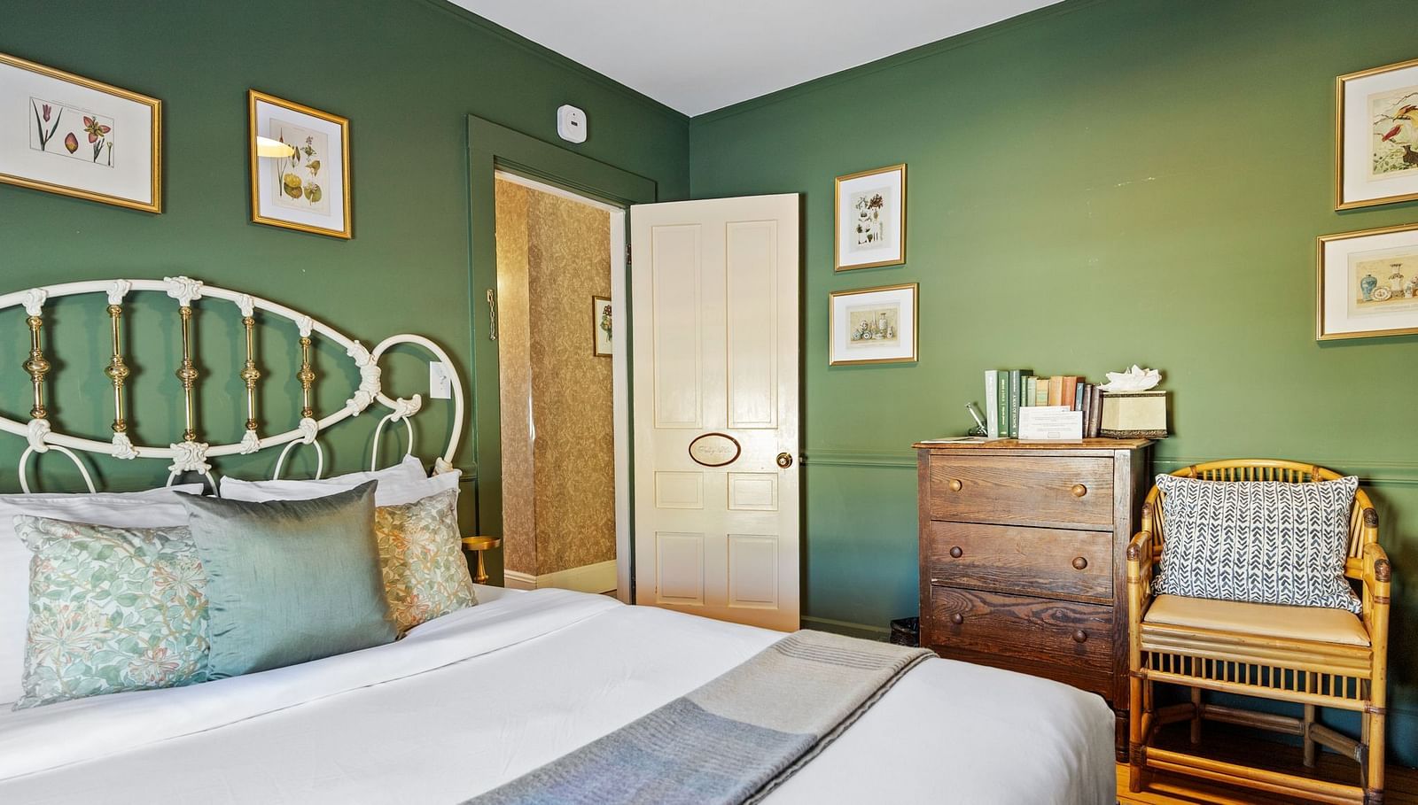 Green-themed bedroom with antique furniture and metal bed frame at Hartstone In