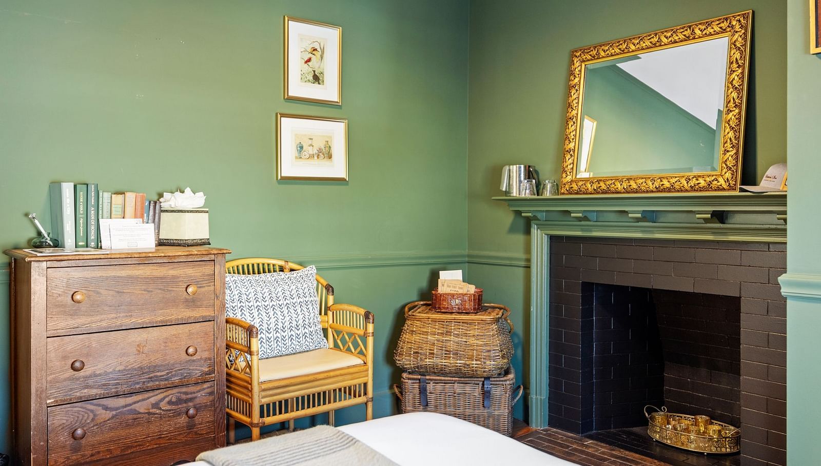 Green-toned bedroom with vintage mirror, fireplace, and wooden table at Hartstone Inn