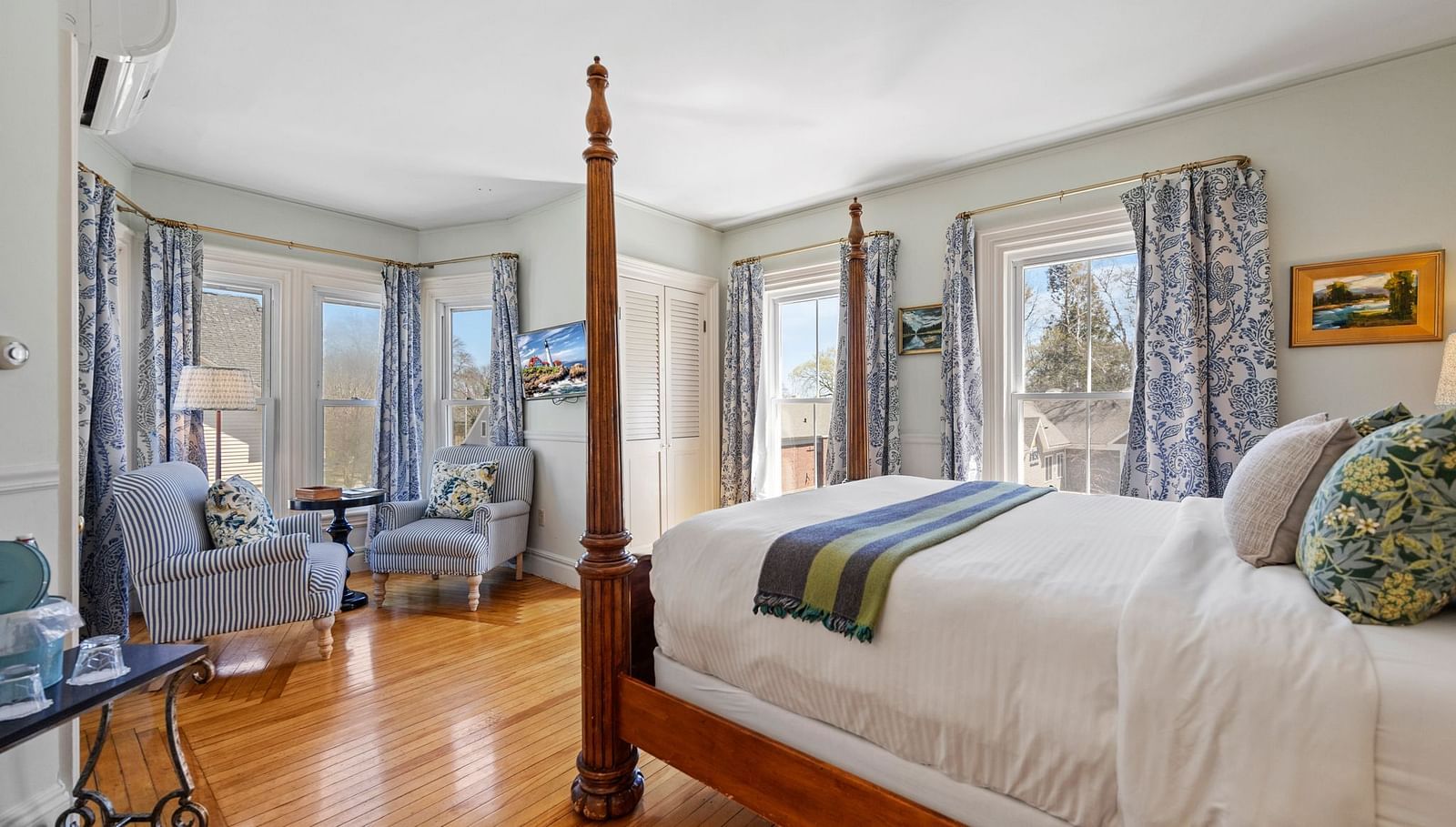 Elegant room with glass windows and dark wood four-poster bed at Hartstone Inn