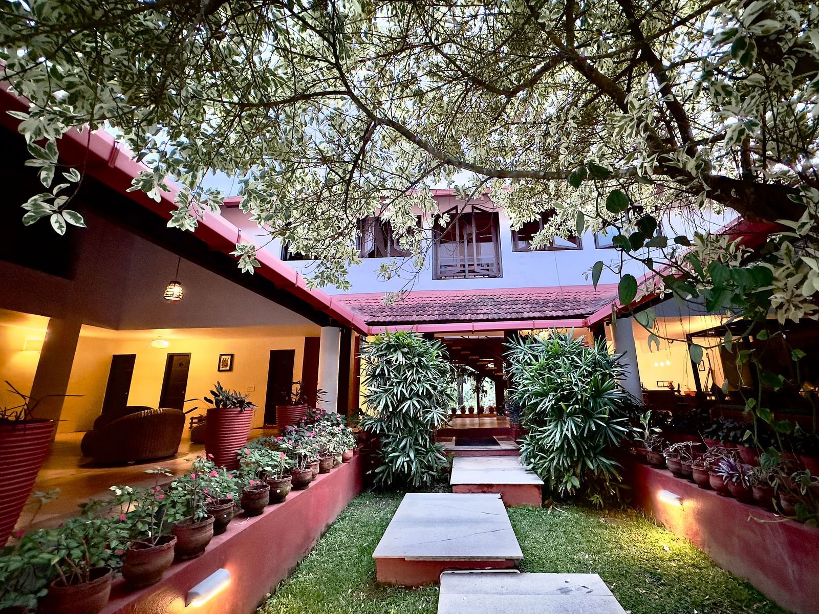 an open area in the interior of the hotel with bushes and flower pots - Kadkani River Resort, Coorg