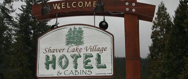 A signboard with the hotel name hanging off a wooden pole at Shaver Lake Village Hotel.