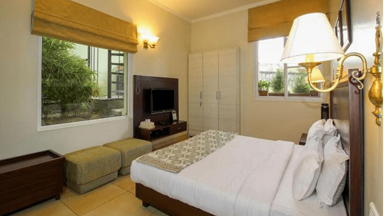 Closer view of deluxe room with tidy white linens and wardrobe on the side along with bedside lamps enhancing the beauty of the room - Lamrin Norwood Green, Palampur3