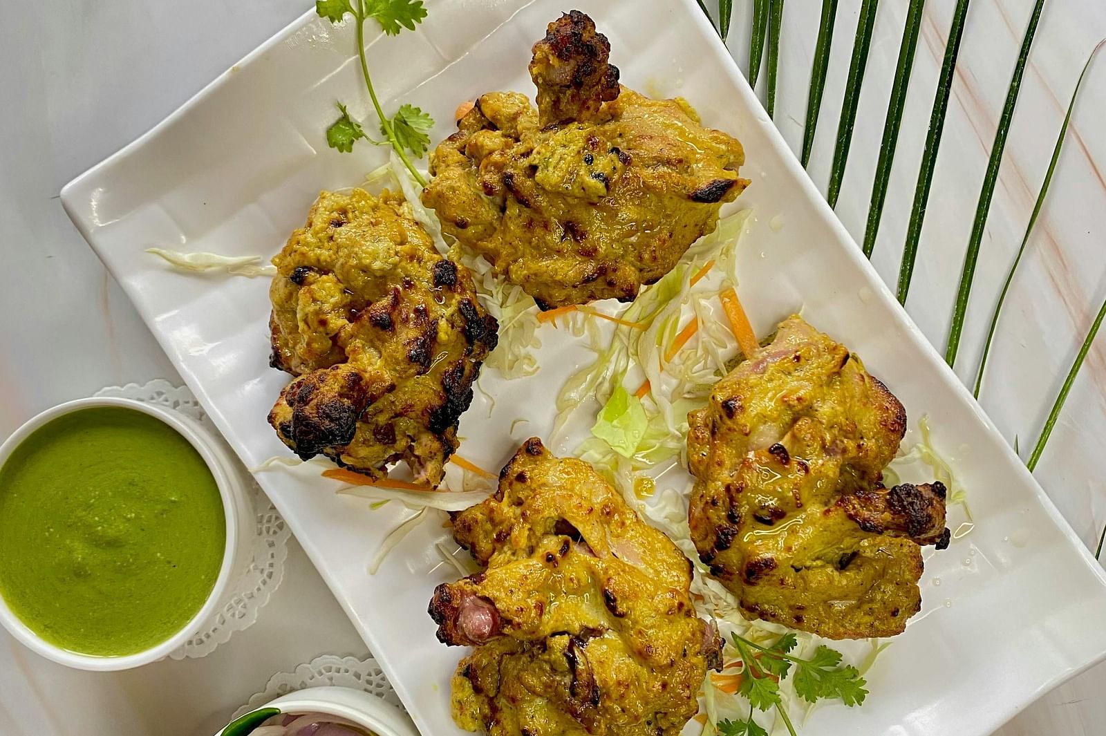 four pieces of grilled meat on a plate with accompaniments