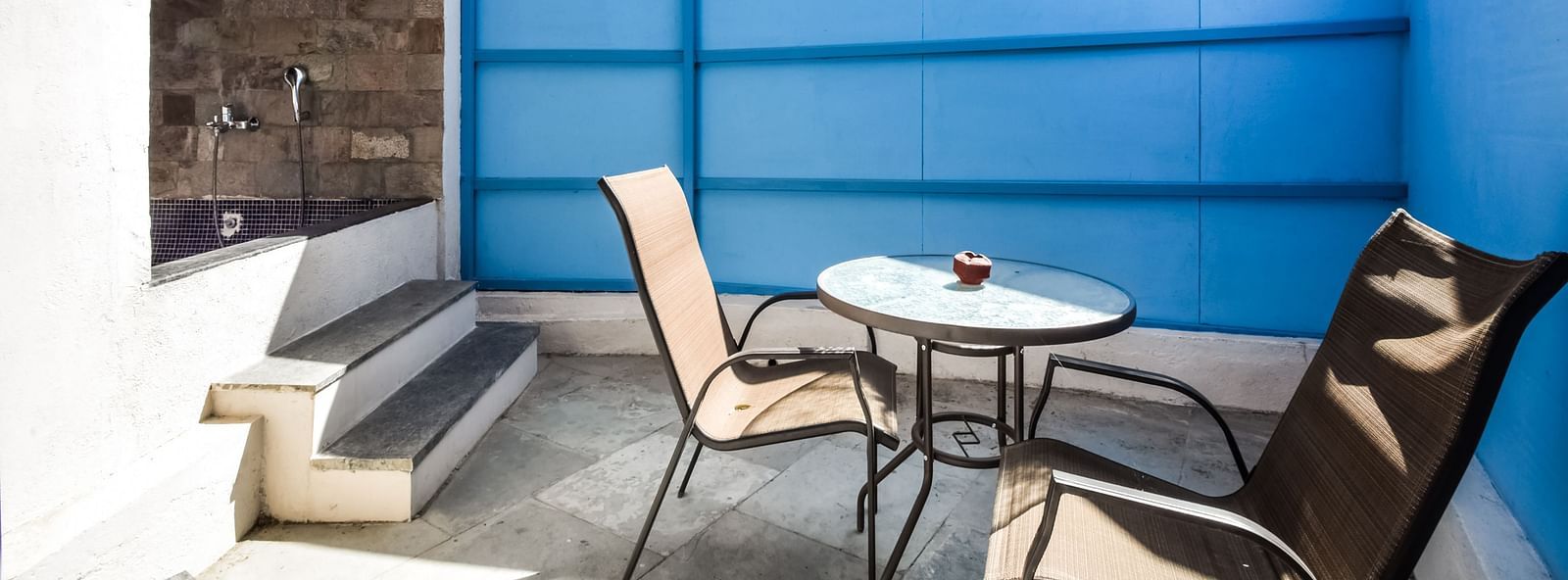 A private patio with two chairs and a table, enclosed by a privacy screen. - Bamboo Saa Resort & Spa, Udaipur