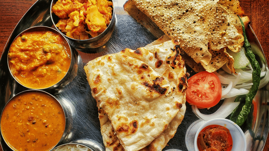 A neatly arranged plate with several Indian delicacies served.