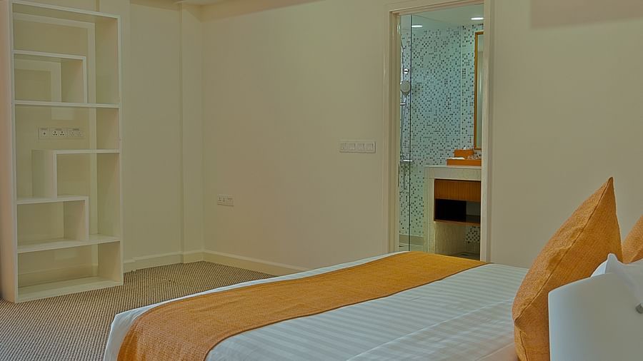A hotel bedroom with a white bed, orange accents, and a mirrored closet door | Penthouse | Central Mansions, Phnom Penh