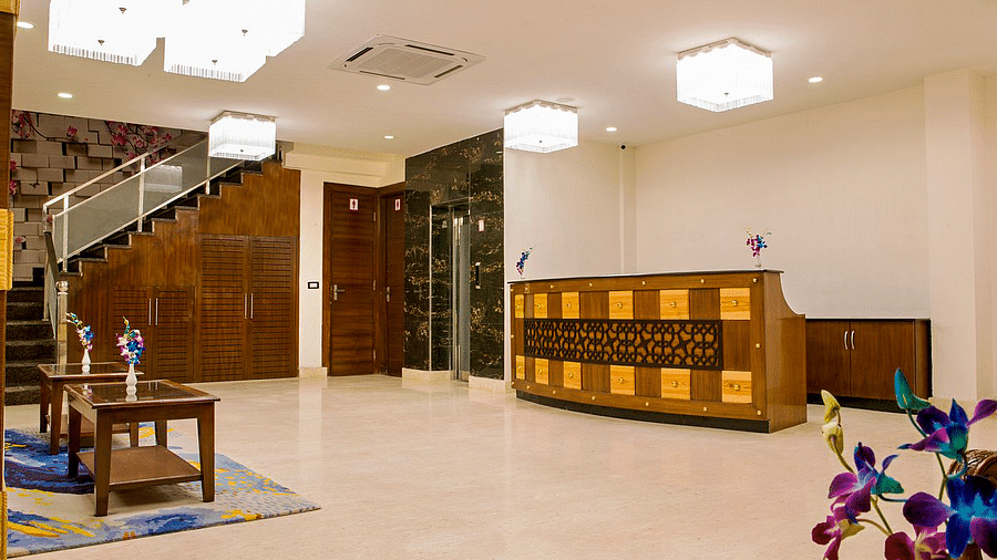 A brightly lit reception area featuring a reception desk in the far end at Regenta Inn DLA.