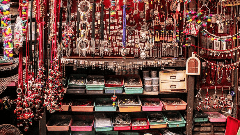A front view of Dhalgarwad, showcasing a vibrant display of colorful bags, jewelry, and a variety of other items for sale, creating a lively shopping atmosphere.