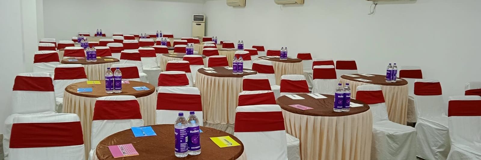 Round tables and chairs covered with cloth, and warm overhead lighting enhance and reside in the Emerald banquet hall of Mountview Resort.